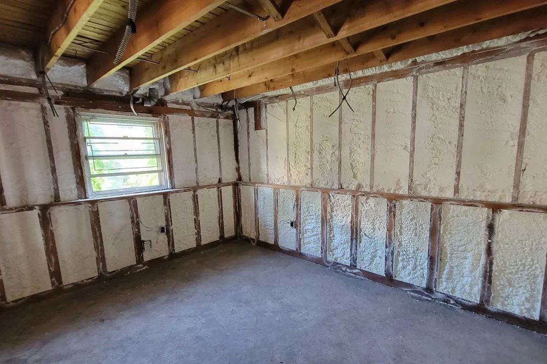 Spray foam insulated walls and window in a gutted basement room