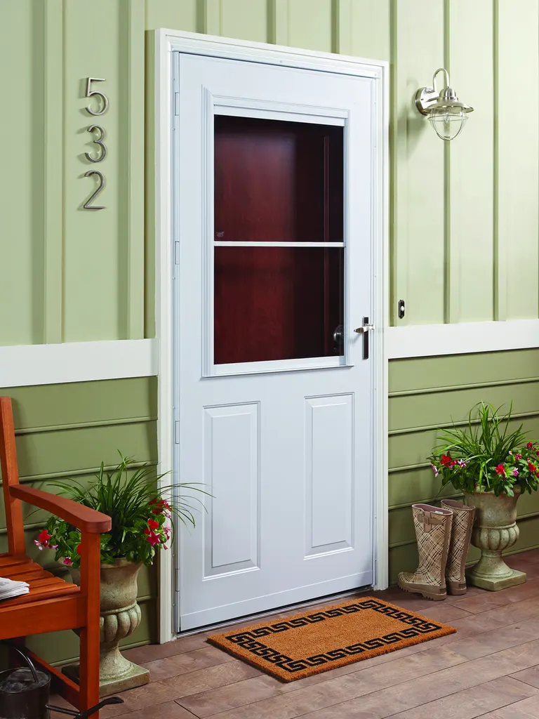 White storm door with upper glass panel installed on a green-sided front porch entry