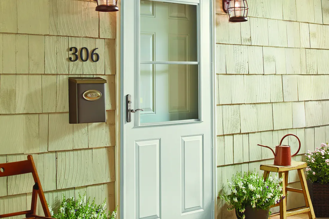 White storm door on a shingled porch with house number 306