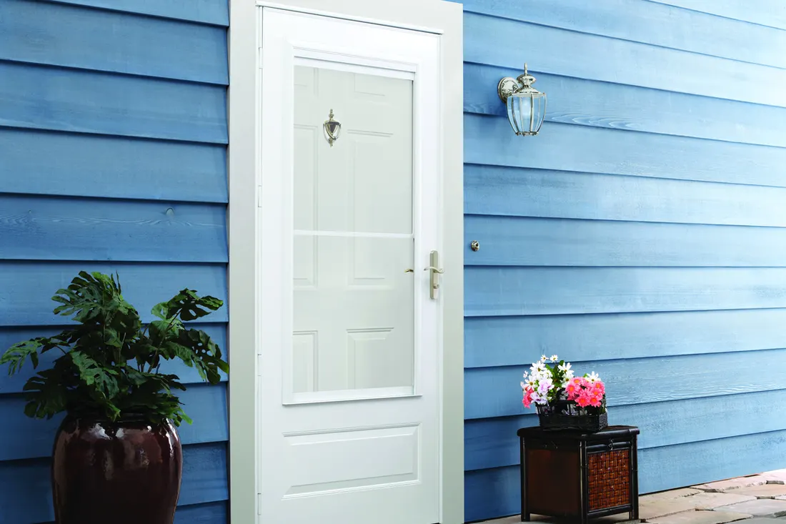 White storm door with glass insert installed on a house with blue horizontal siding