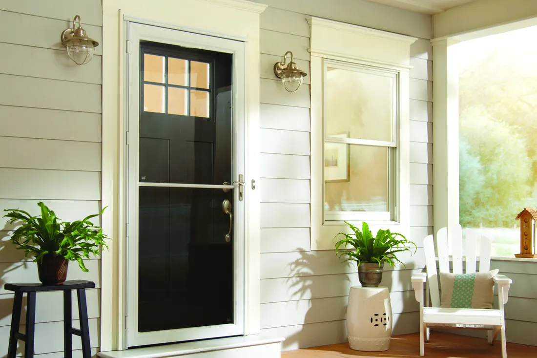 Black storm door with divided glass on a white cottage porch