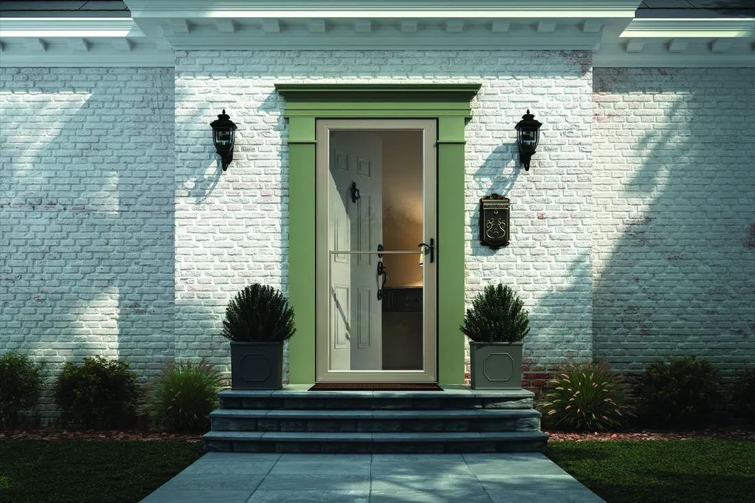 Glass storm door installed on a white painted brick house with green trim frame