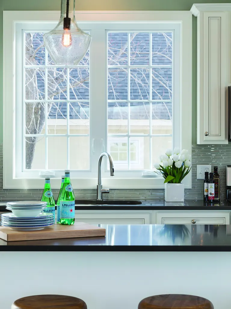 White multi-pane casement window set above a kitchen sink with dark countertops
