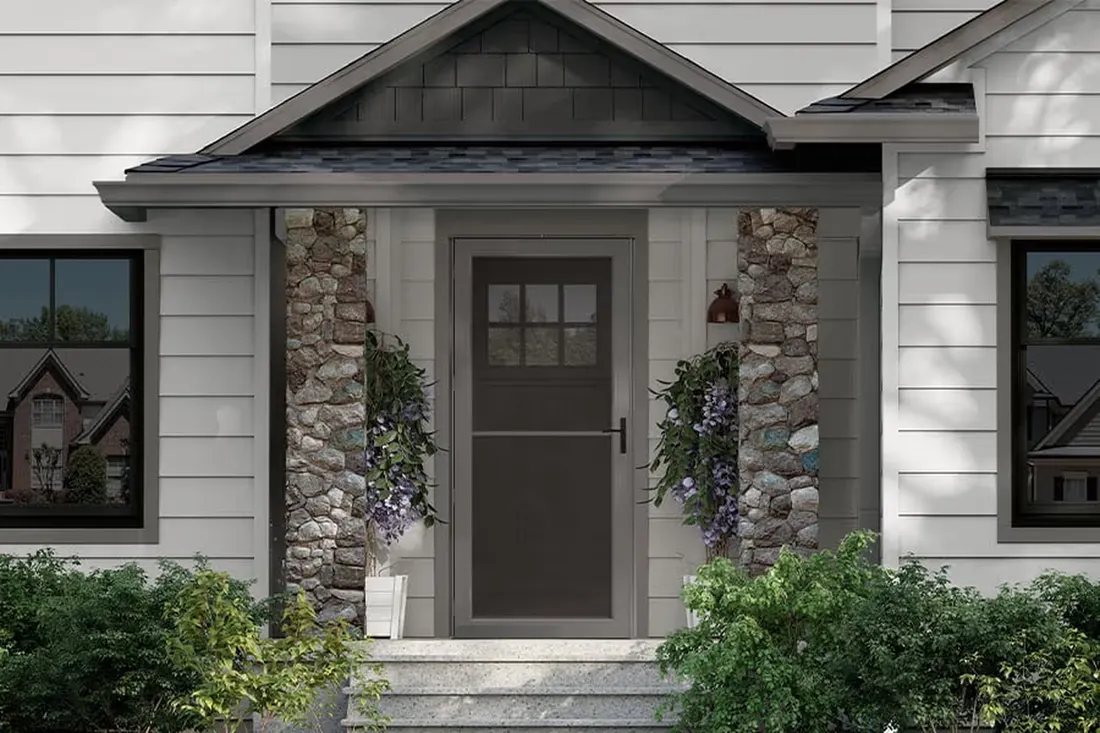 Dark gray storm door with glass panes on a front porch with stone pillars