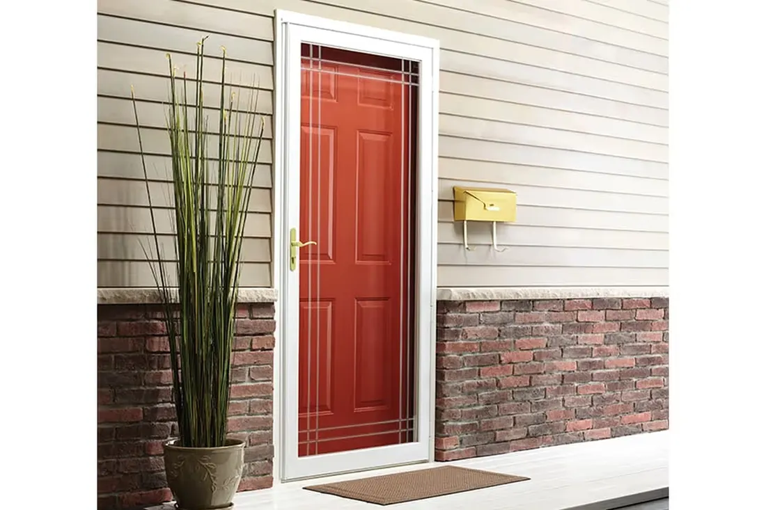 White storm door with decorative glass over red front door on brick and siding house