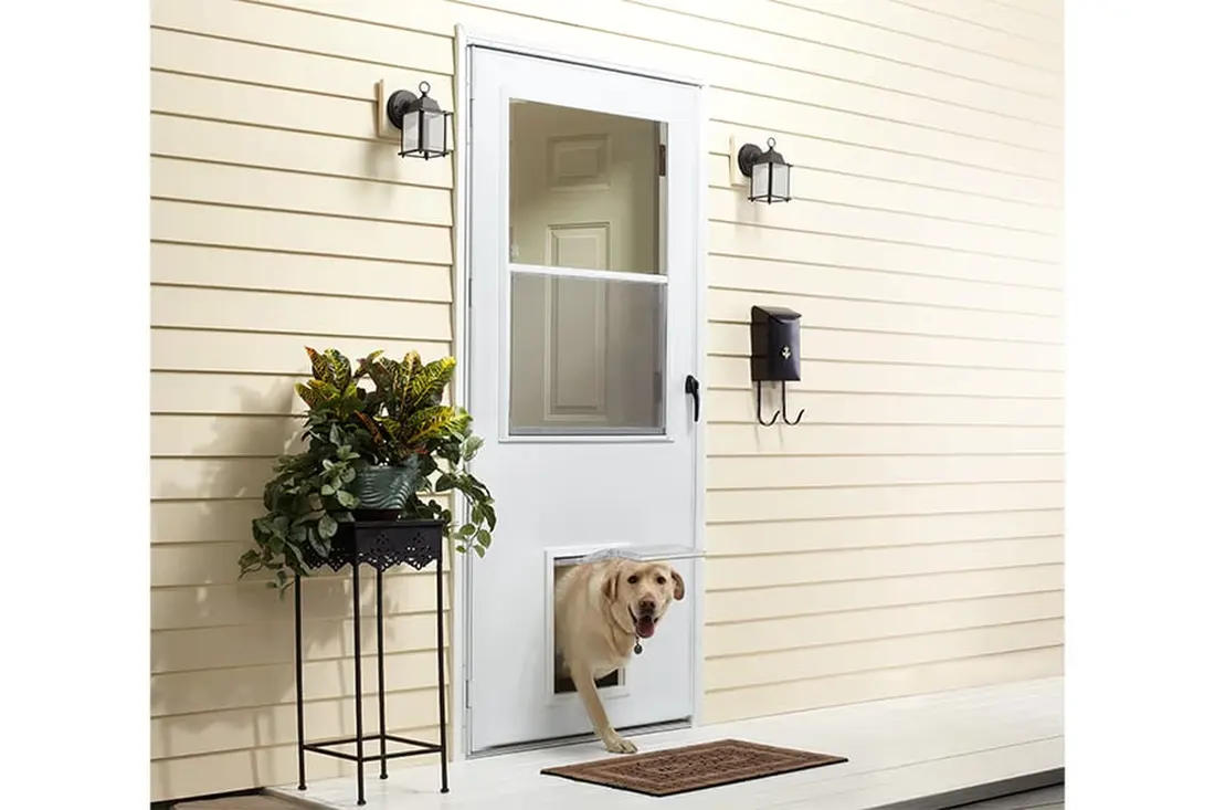 White storm door with a built-in pet flap installed on cream vinyl siding