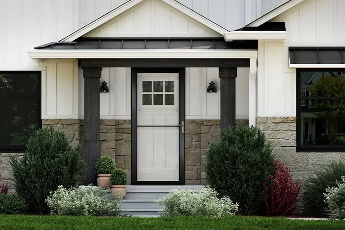 Black storm door installed over a white front door on a covered stone porch