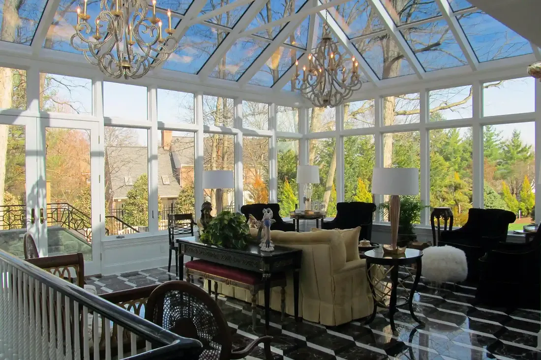 Sunroom with white framed glass walls, vaulted glass ceiling, chandeliers, and black-and-white checkered floor