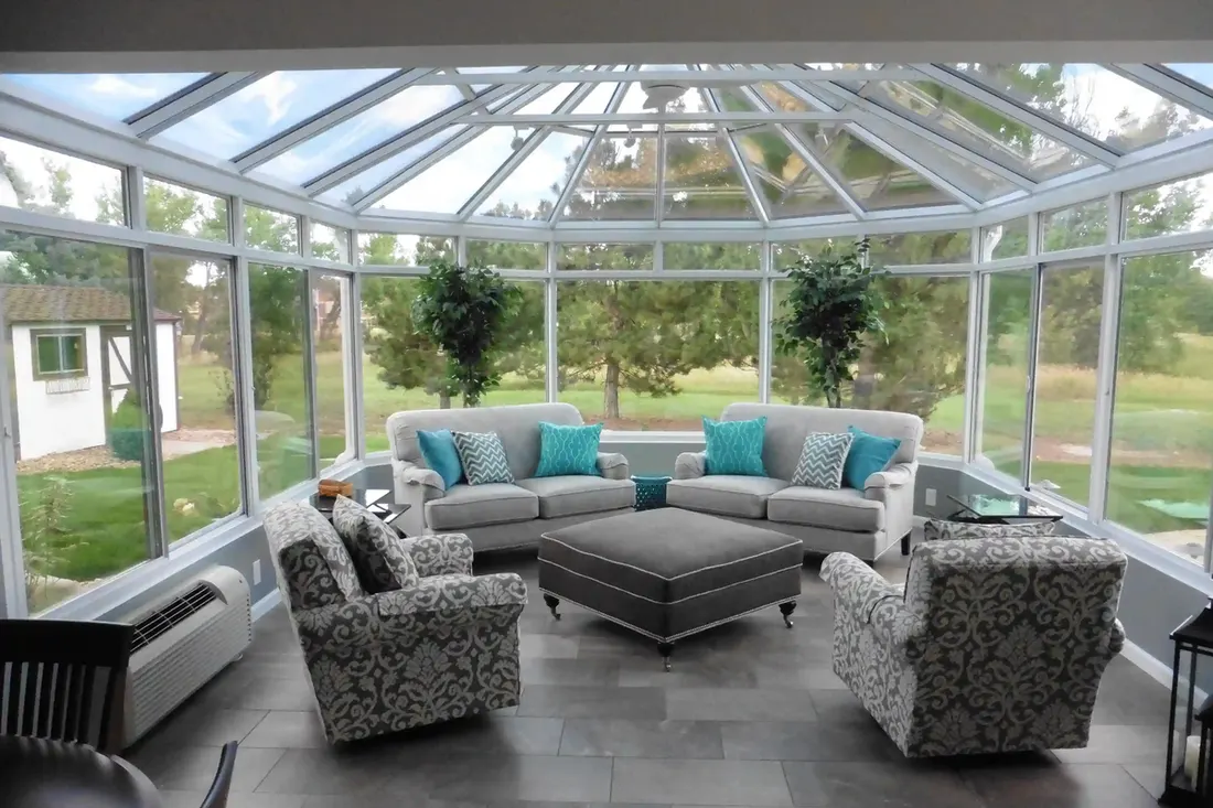 Conservatory sunroom with a glass roof and gray lounge furniture
