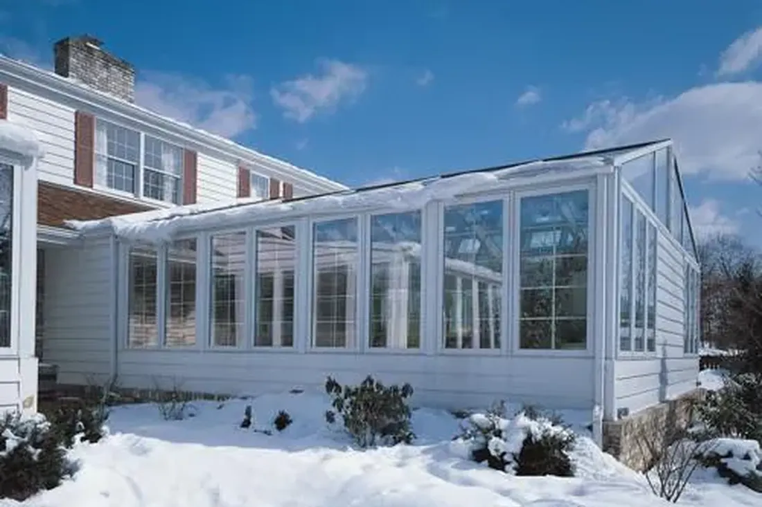 White glass sunroom addition on a home in a snowy yard