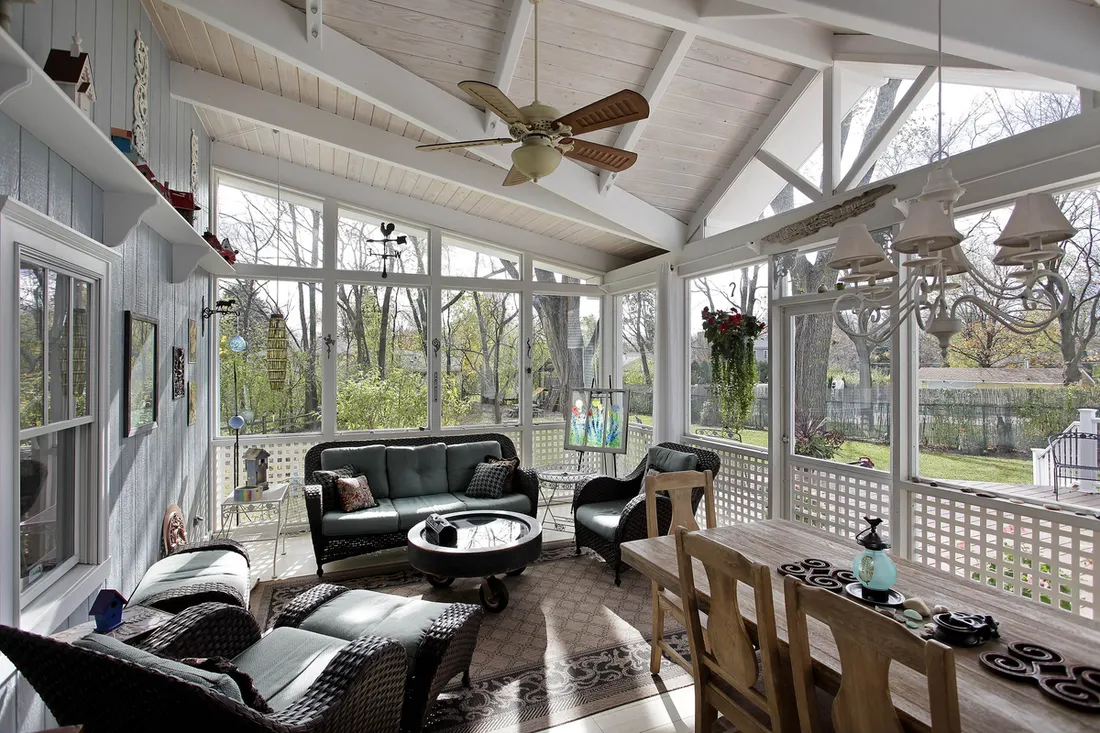 Screened porch with white beams, ceiling fan and dark seating