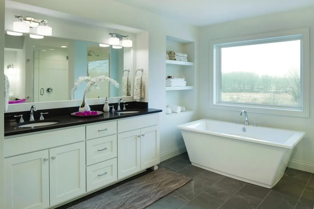 Large picture window with white trim above a freestanding soaking tub in a modern bathroom