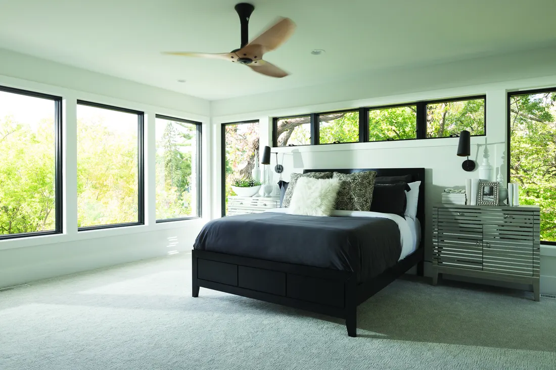 Bedroom with large black-framed picture and clerestory windows overlooking green trees