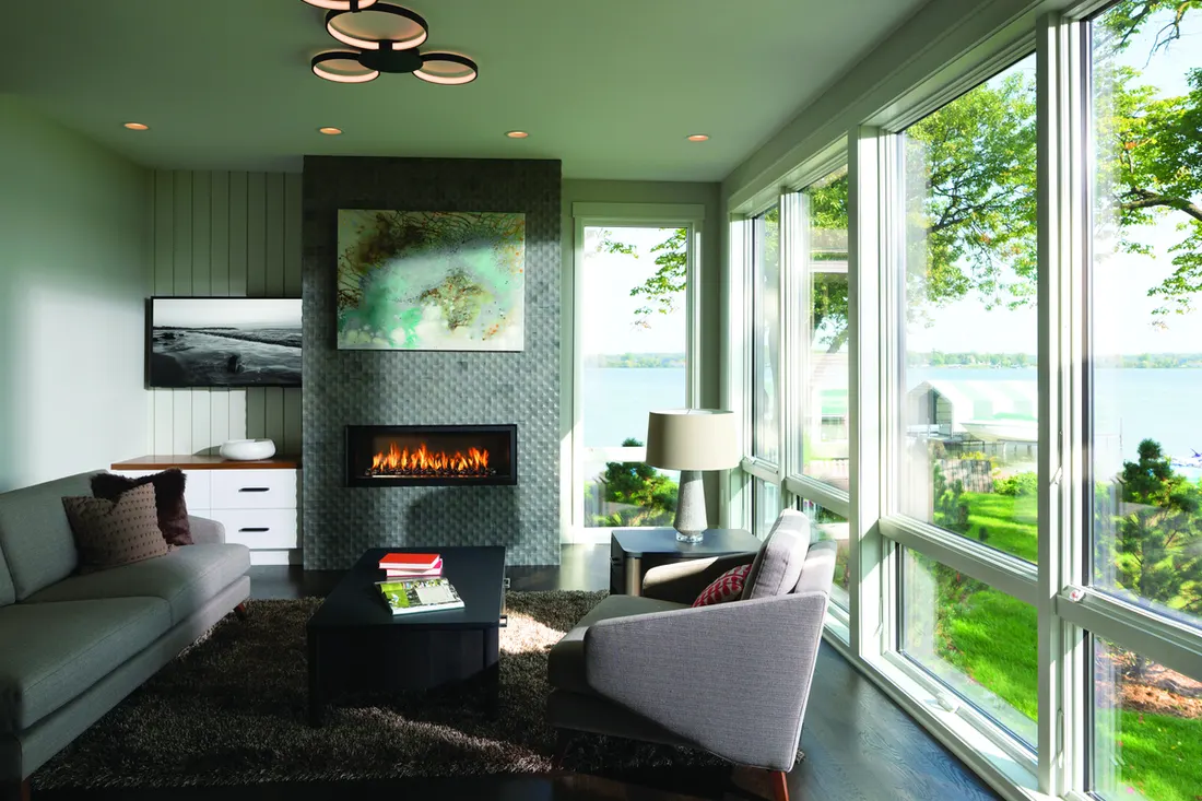 Large floor-to-ceiling white-framed windows in modern living room overlooking a lake and trees