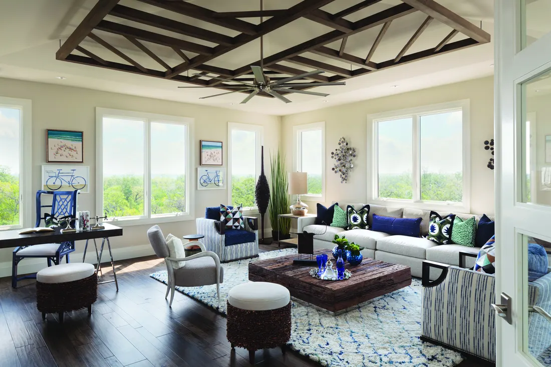 Bright living room featuring white-framed sliding windows offering lush green outdoor views