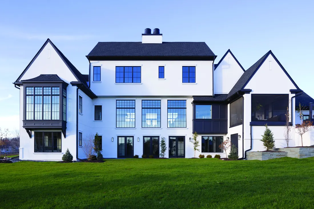 Modern home with white siding, black trim, and large grid windows against a green lawn