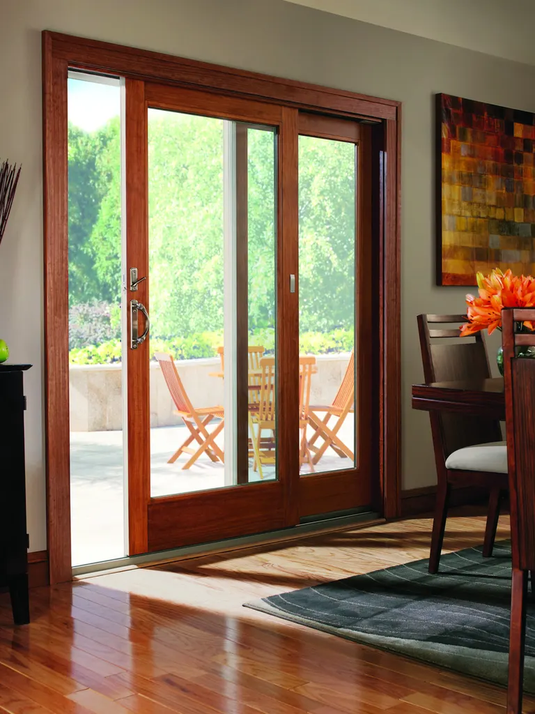 Sliding glass patio door with warm wood trim opening to an outdoor stone terrace