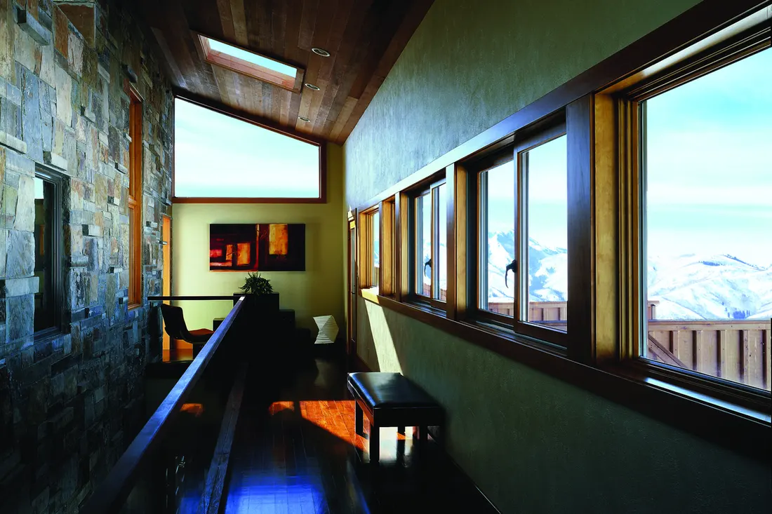 Long hallway featuring wooden framed windows, stone wall, skylight, and scenic mountain views outside